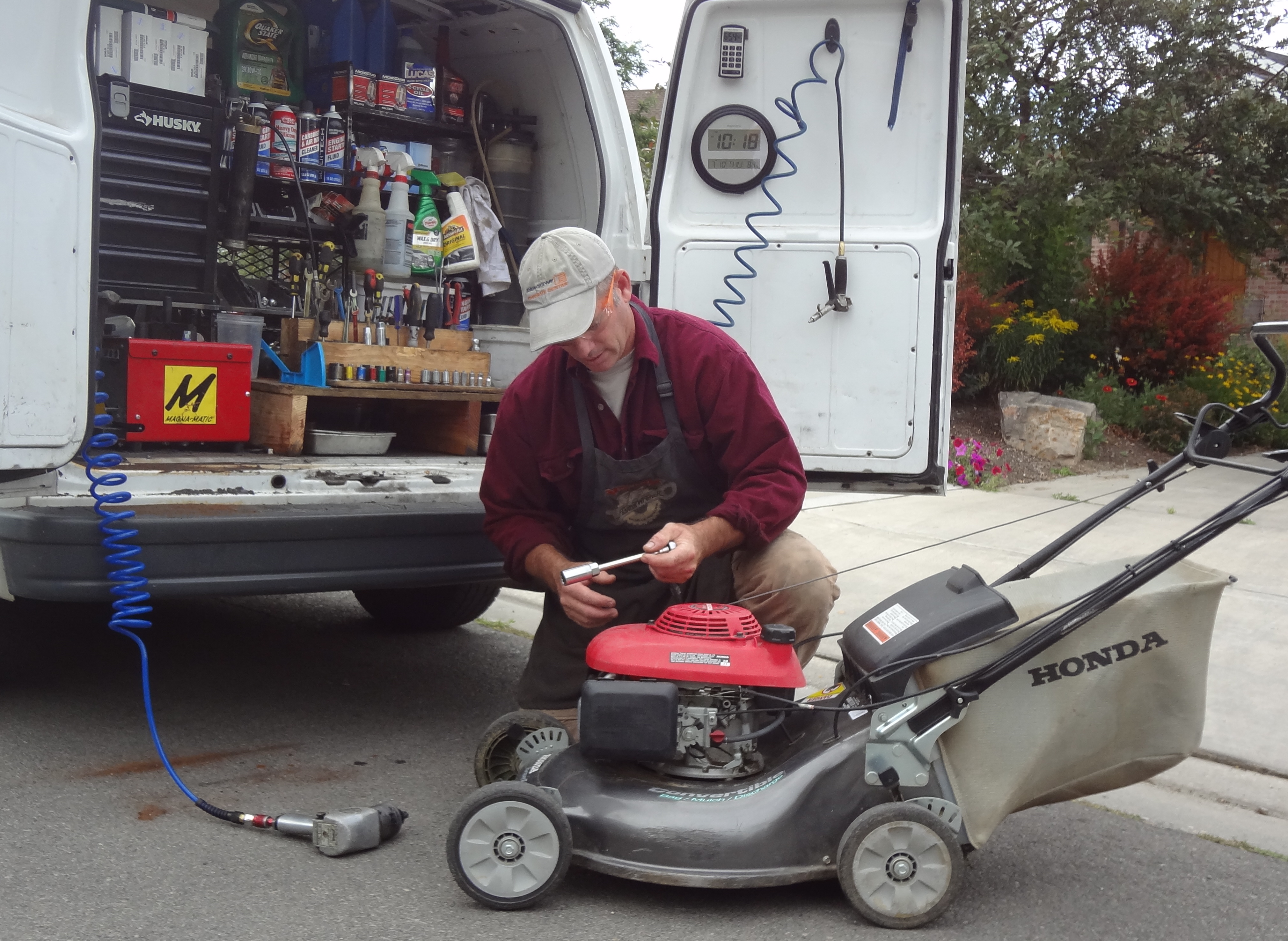 Man servicing a honda lawn mower behind a white van Whats included in a lawn mower service
